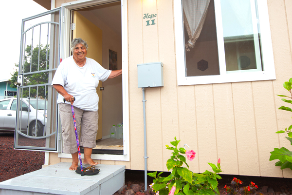 A person smiles, standing on the porch of a modular home.