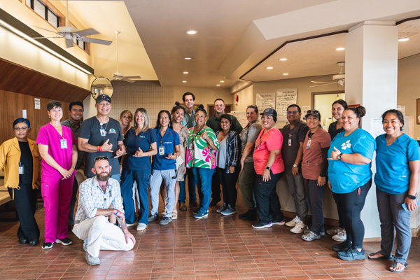 A group of people smiling and posing for a photo in a hospital, capturing a moment of togetherness and celebration.