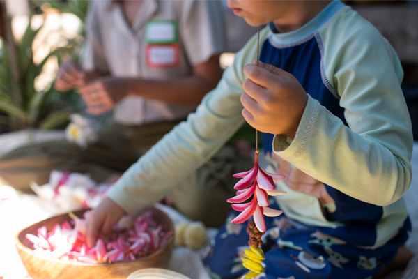A young boy carefully crafting flowers with his hands, showcasing his artistic skills and creativity.